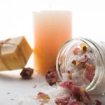 Sales de baño con pétalos de rosa, jabón artesanal y vela para una experiencia de bienestar natural.